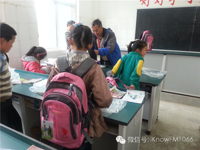 志愿者在教孩子們?nèi)绾畏艑捄褪站o書包的背帶！