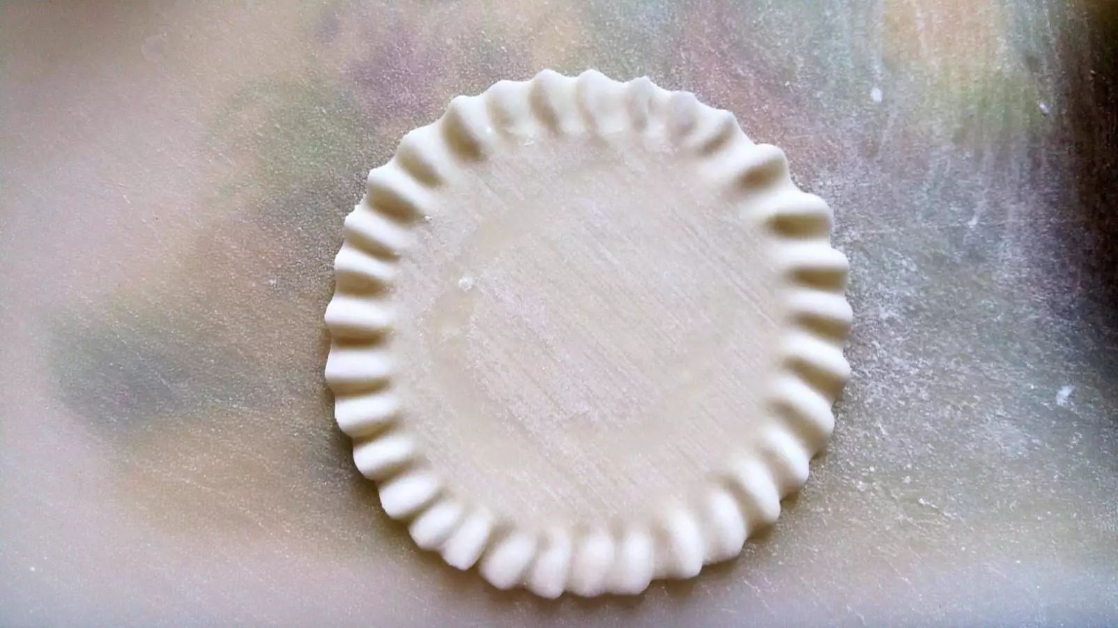用一块饺子皮,把边缘用拇指和食指推捏出荷叶边.