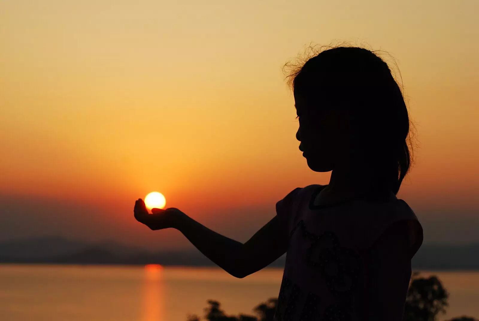 夕阳西下时,连活泼好动的小女孩也驻足,用手留住了一个神奇的梦.