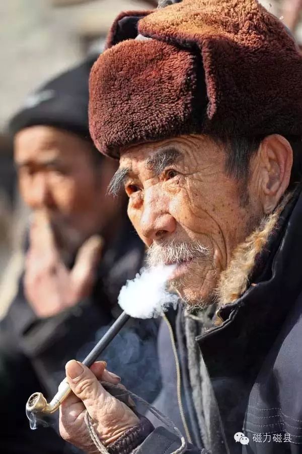抽着旱烟,带着大棉帽,老人眼神里带着坚定,慈祥.