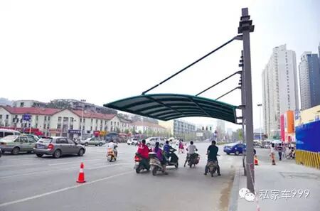 路建设路口，市民在遮阳棚下等红绿灯