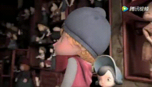 小女孩刚想拿起桌上的洋娃娃,却被地上一个骑着自行车的男孩玩偶绊到