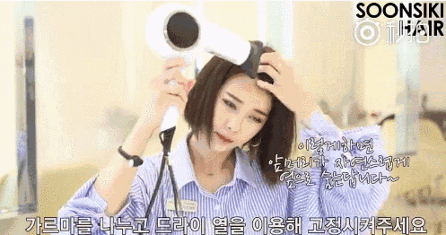 step3：拿卷梳放在分界线一边按在头发上，将头发往分界处轻推，用吹风机来回吹几下。