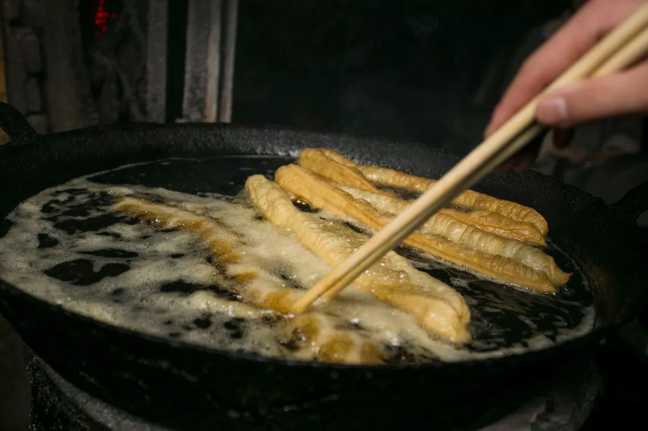 待油锅中的油条饱胀鼓起,颜色由白色变为金黄,便把炸好的油条一根一根