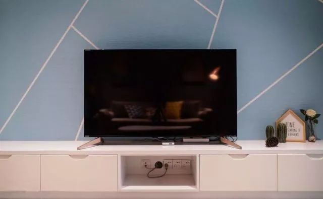 客厅的背景墙以蓝色背景与白色的几何线条,电视柜巧妙地收纳插座电线