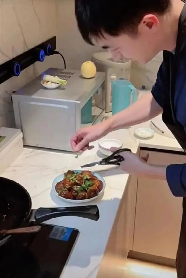 厨房台面上正在摆盘的下厨画面，体现台面材质与插座布局的实用性