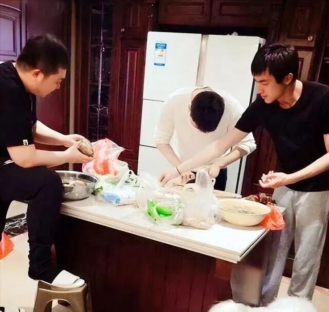 厨房岛台上多人一起备菜操作，展示岛台作为备餐与互动的核心