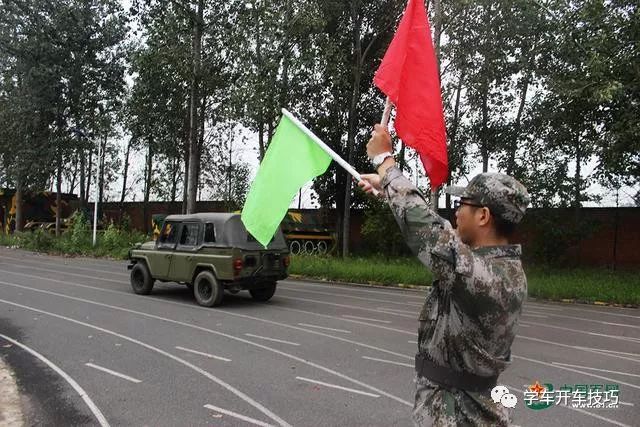 学员在旗语指令下驾驶军车.