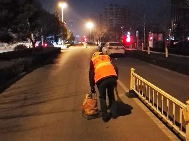 清晨5:40,烟台路上,晕黄的路灯映着保洁员秦秀芬躬身如桥的背影.