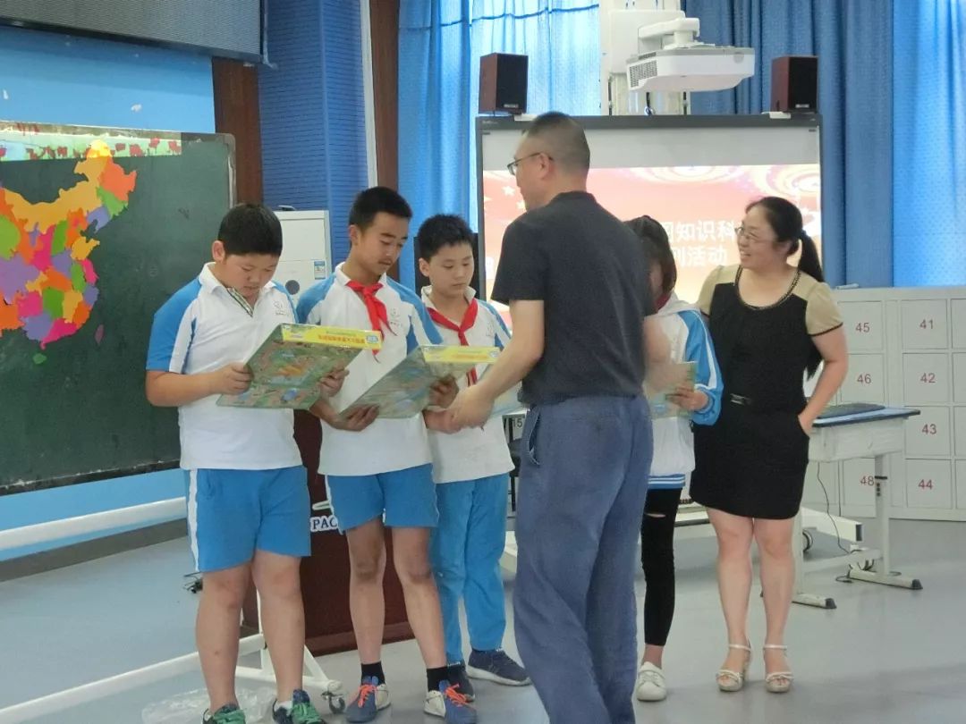 成都地图出版社副总编张忠向泡桐树小学蜀都分校学生颁发奖品