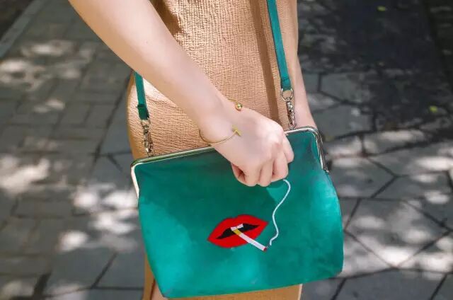 搭配：橘色抹胸包臀长裙＋低跟尖头玛丽珍鞋＋墨绿色单肩包＋慵懒复古妆＋蓝色闪片耳饰