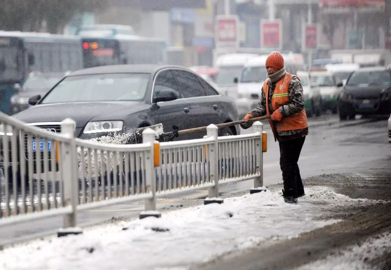 (在解放中路上,一位环卫工人冒雪在路中间清雪)