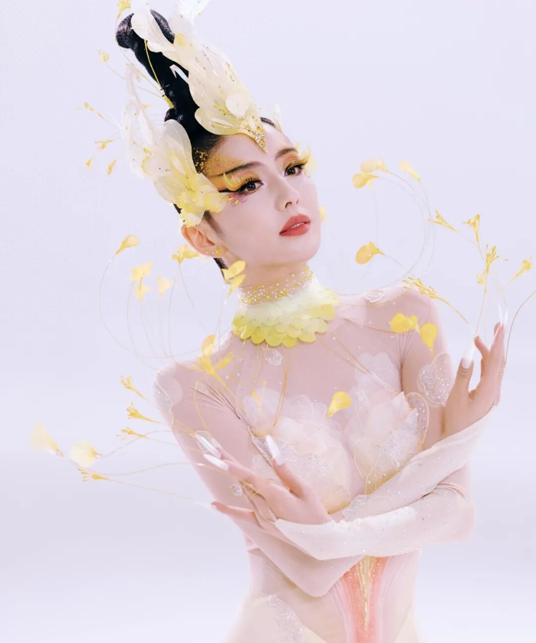 佟丽娅身着黄色羽毛服饰，妆容精致，姿态优雅