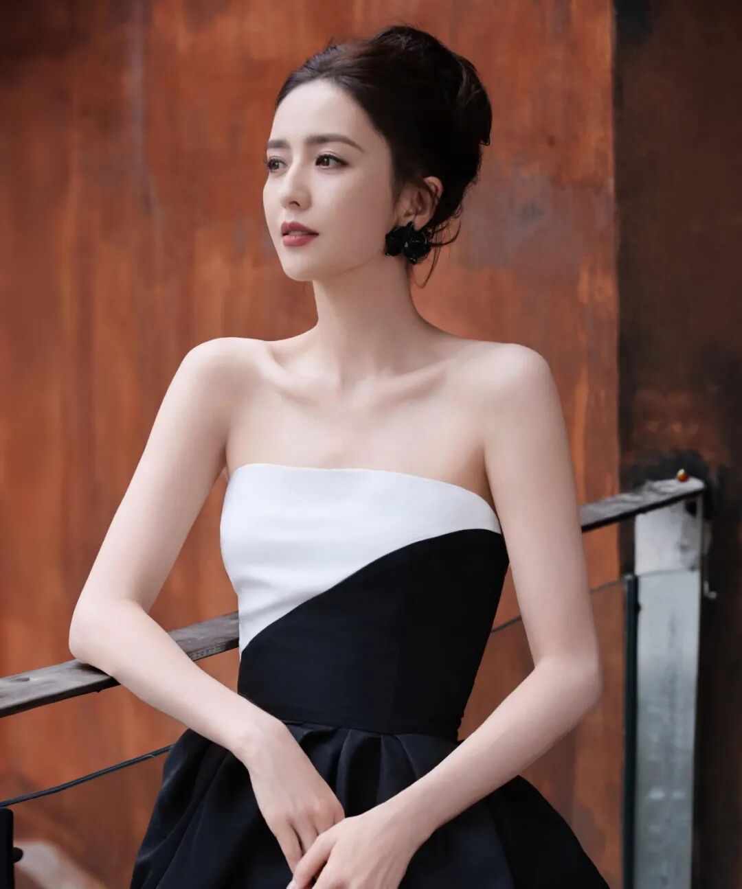 美丽女性身着黑白礼服，红唇黑花耳环，发型发髻