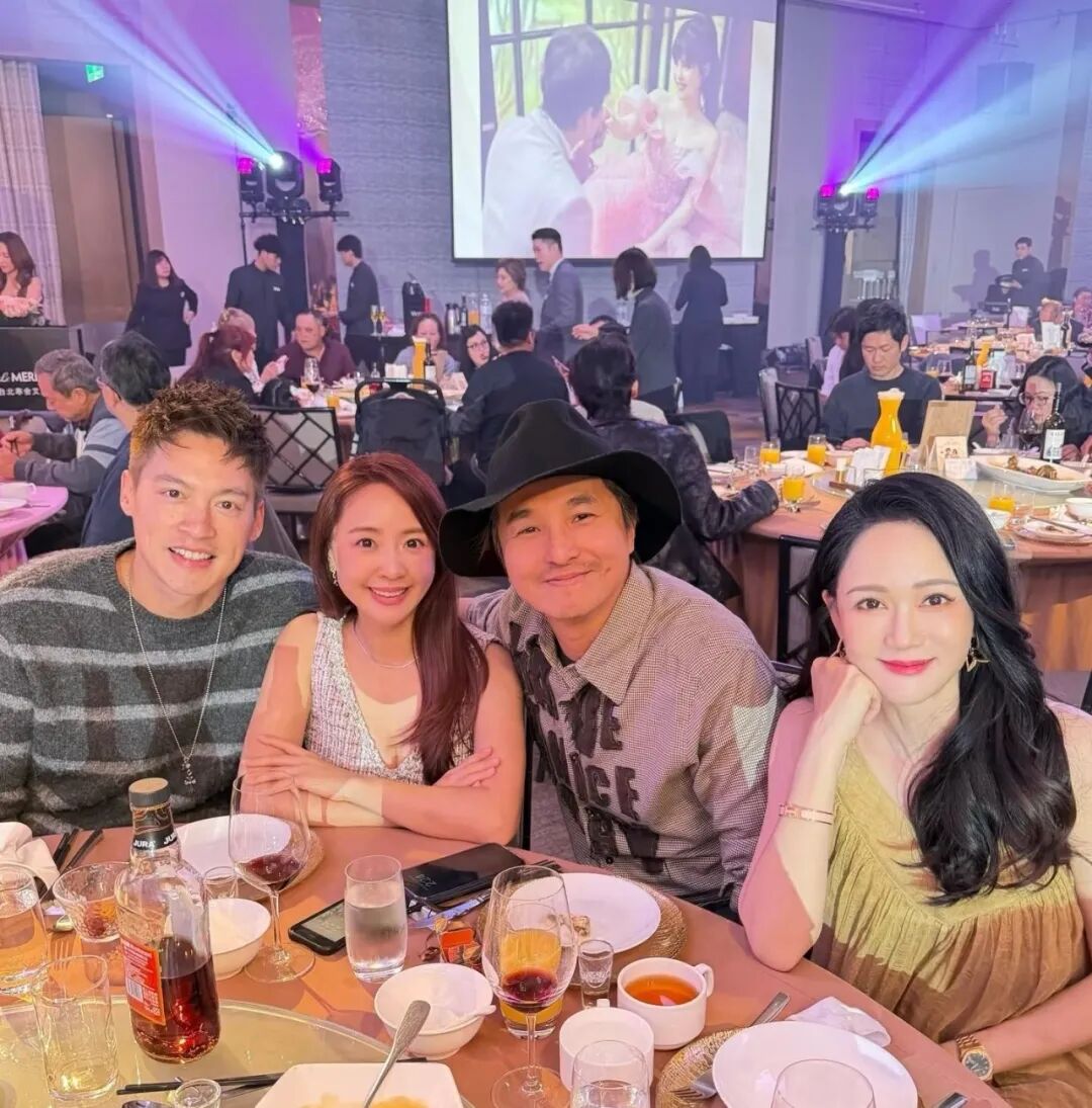 Four people are sitting around a table filled with drinks and food