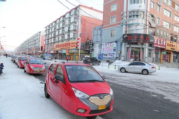 图注:亚布力镇街道,路边停靠着一排红色港田,等着客人前来