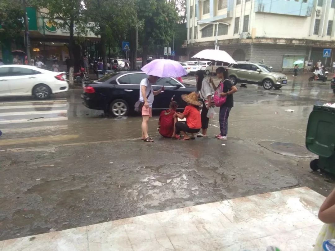 雨天路滑老人摔倒在拉堡街上,小姑娘孤独帮他打着伞,随后