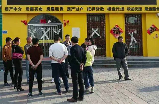安新县湿地华城楼盘外聚集的外地购房者，房产中介已贴上封条。