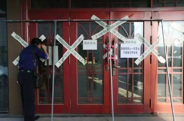  一名外地购房者在明珠湾楼盘销售中心外向内观看。 