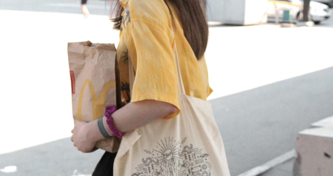 woman in yellow long sleeve shirt holding brown paper bag