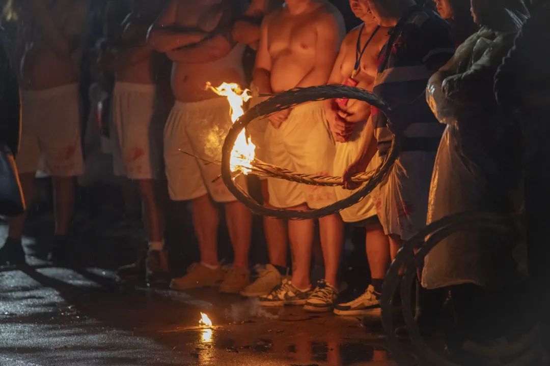 火龙队伍在街上巡游时，村民拿着燃烧的草绳圈为队伍开道