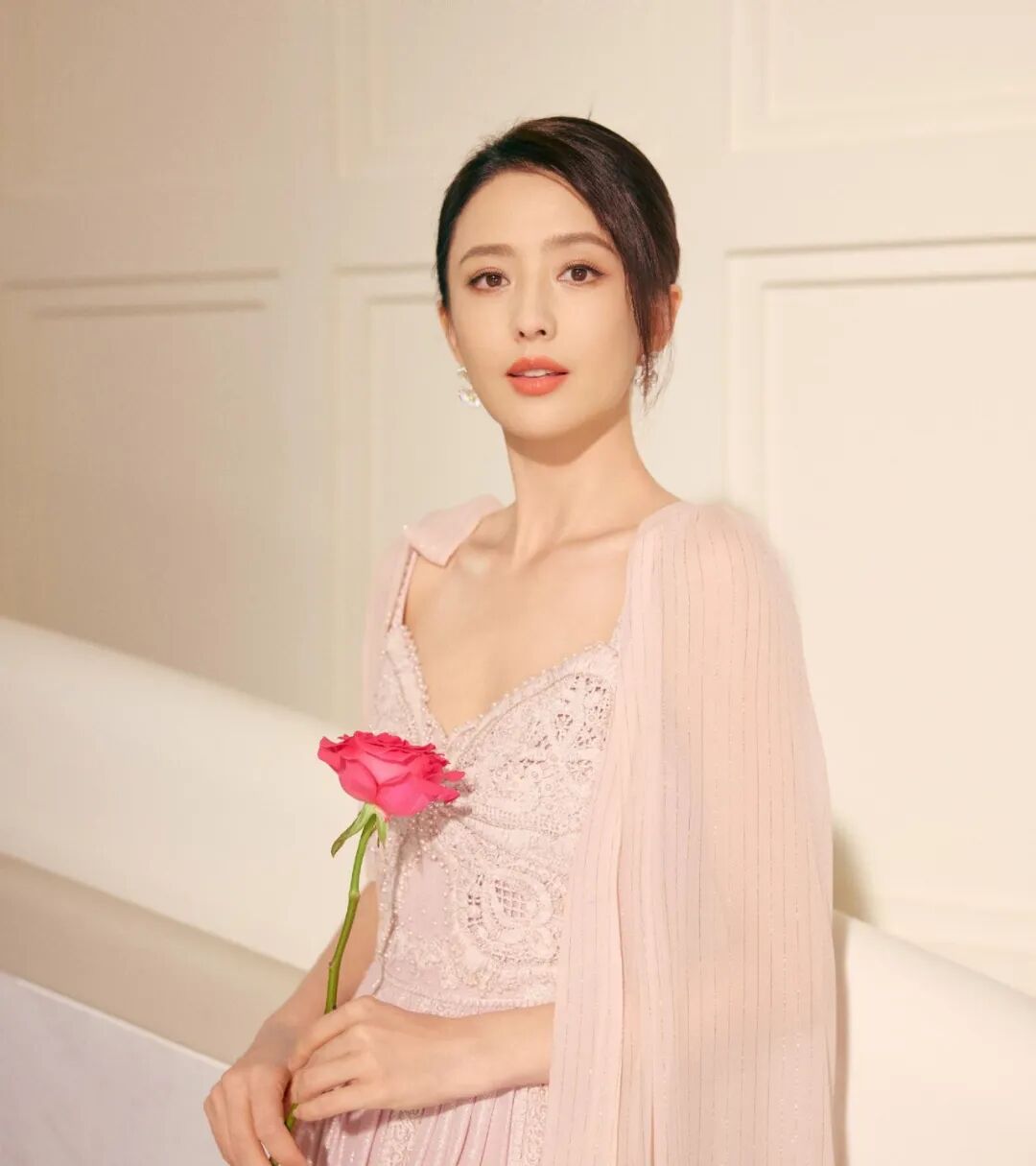 女性身着粉色长裙手持玫瑰