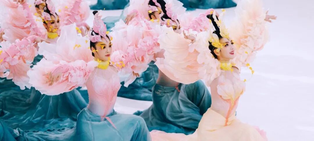 一群表演者身着花卉般服饰和头饰摆姿势表演