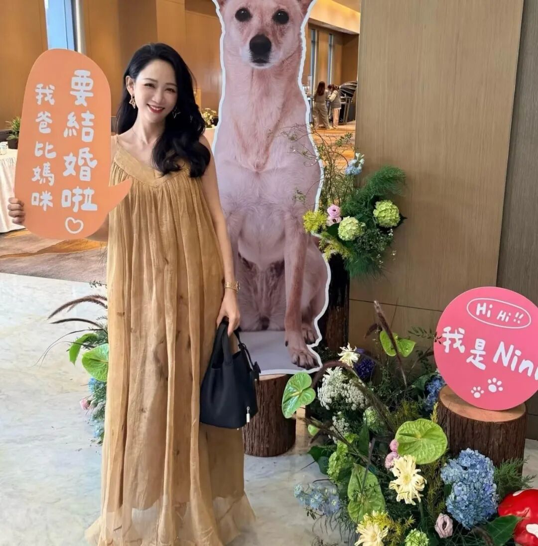 Woman poses next to a cardboard cutout of a dog and a pink sign written with Hi, Hi! I'm Nini.