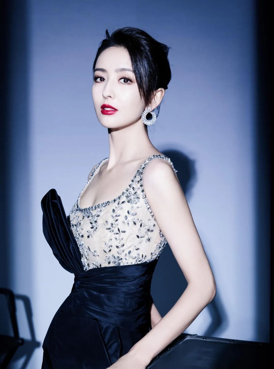 美丽东亚女性身着黑银色礼服，红唇妆容，背景深灰