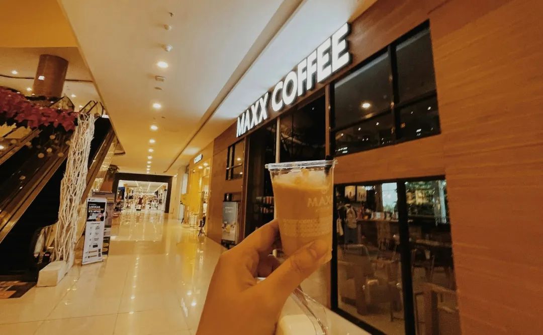 a person holding a drink in front of a coffee shop