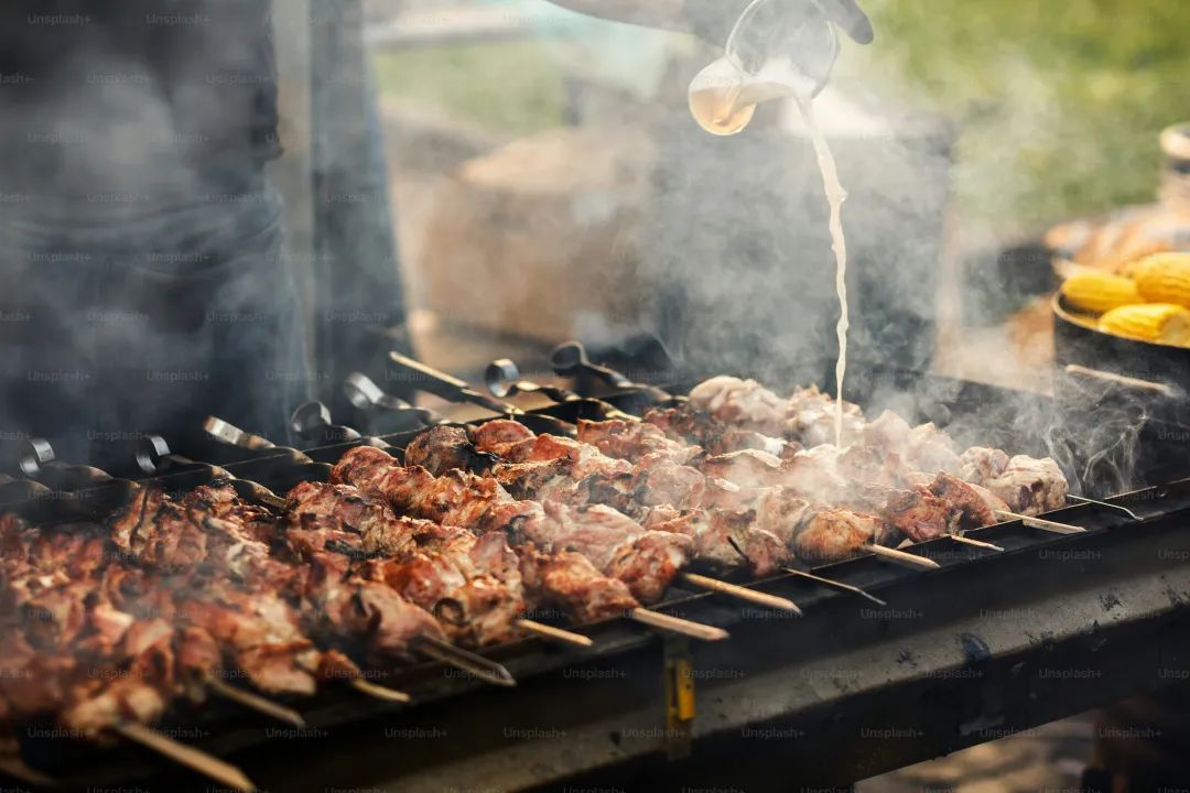 delicious bbq kebab grilling on open grill, outdoor kitchen. food festival in city. tasty food roasting on skewers, food-court. summer picnic