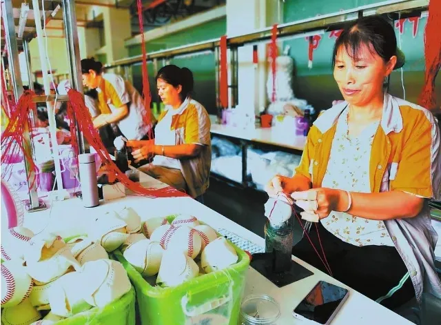 搬迁群众在怒江州泸水市和谐社区棒球帮扶车间里缝制棒球。李寿华 摄.png