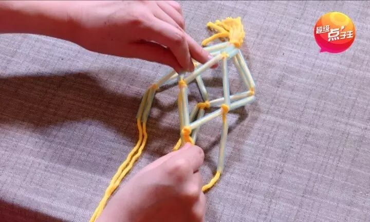 再次将每根毛线都穿过吸管,像下图这样把中间的绳子打结,让中间出现一