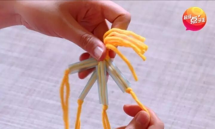 再次将每根毛线都穿过吸管,像下图这样把中间的绳子打结,让中间出现一