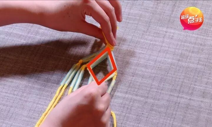 再次将每根毛线都穿过吸管,像下图这样把中间的绳子打结,让中间出现一