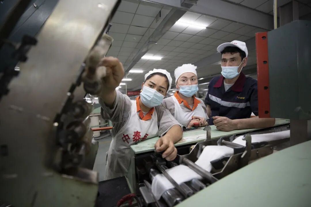 ▲艾山江·阿布都拉在为新员工讲解生产工作，帮助她们尽快适应工作岗位。