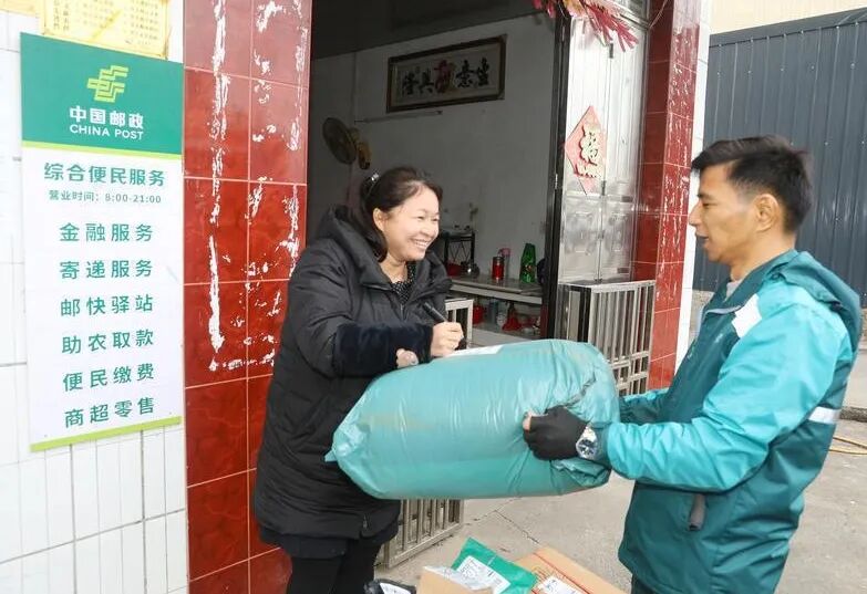 位于连平县三角镇阳江村的邮政综合便民服务站，邮递员给村民配送包裹。
