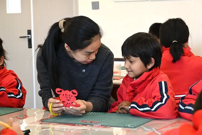 在疏附县托克扎克镇中心小学的社团课上，陆婉静教学生们剪纸。