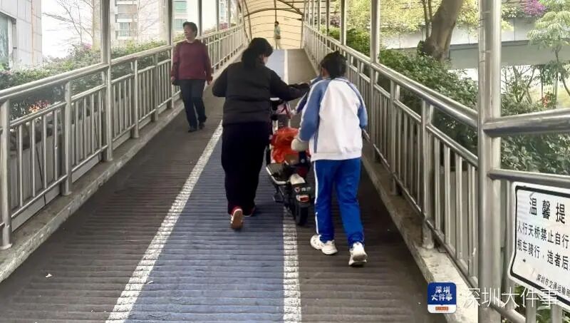 因人行天桥坡度太大，骑电动自行车的市民只能下车推行方能上去。
