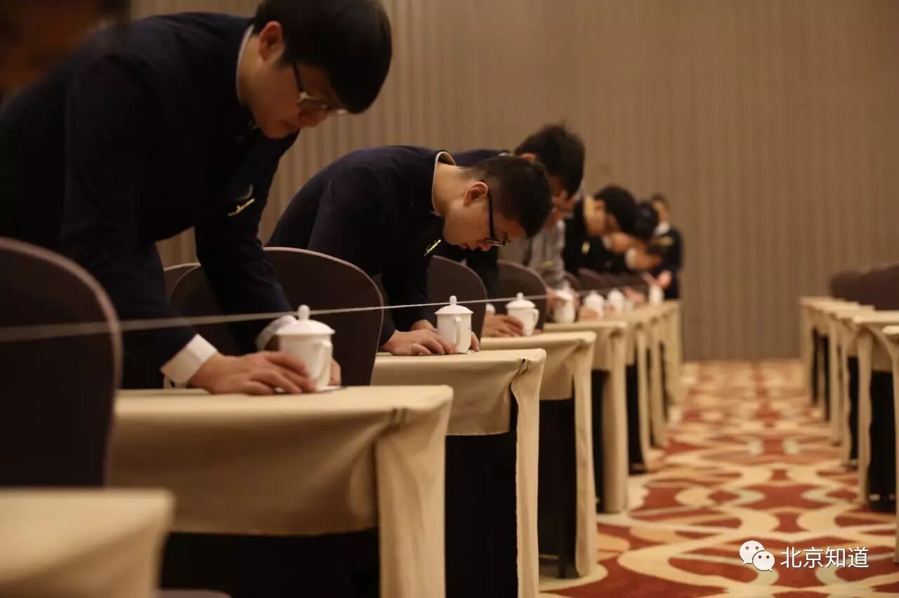 大会议室里正有服务员在布置,他们用一条细绳子比量座椅的位置,水杯也