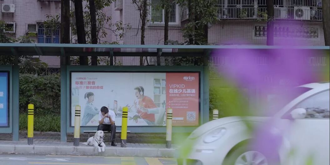 （图）传锡在公交站上使用手机