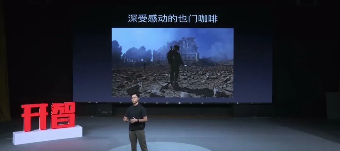 吴三岁站在台上，身后幻灯片写着「深受感动的也门咖啡」，配图是战火废墟
