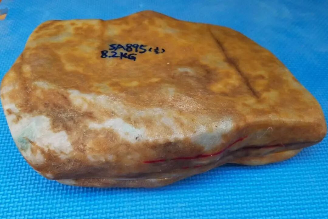 一块黄迹斑斑的翡翠原石，一刀截断，片片金黄，道道裂痕！