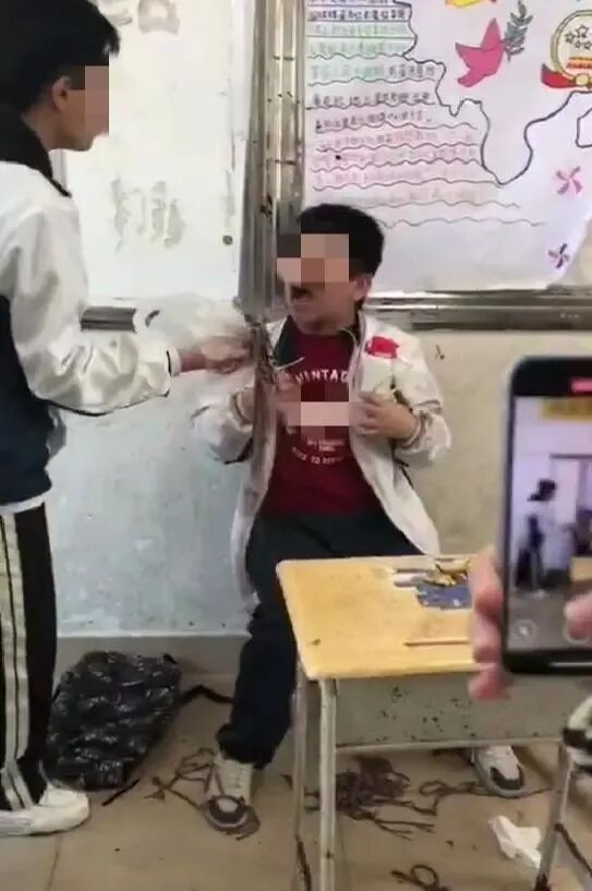 “校服男生”张开嘴后，对方欲将该异物强塞进去