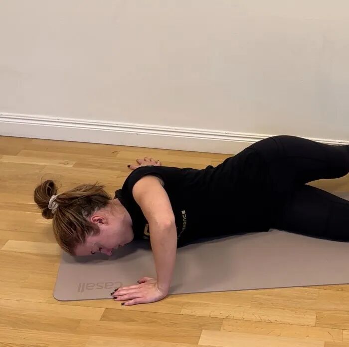A photo of a woman doing a lying chest stretch.