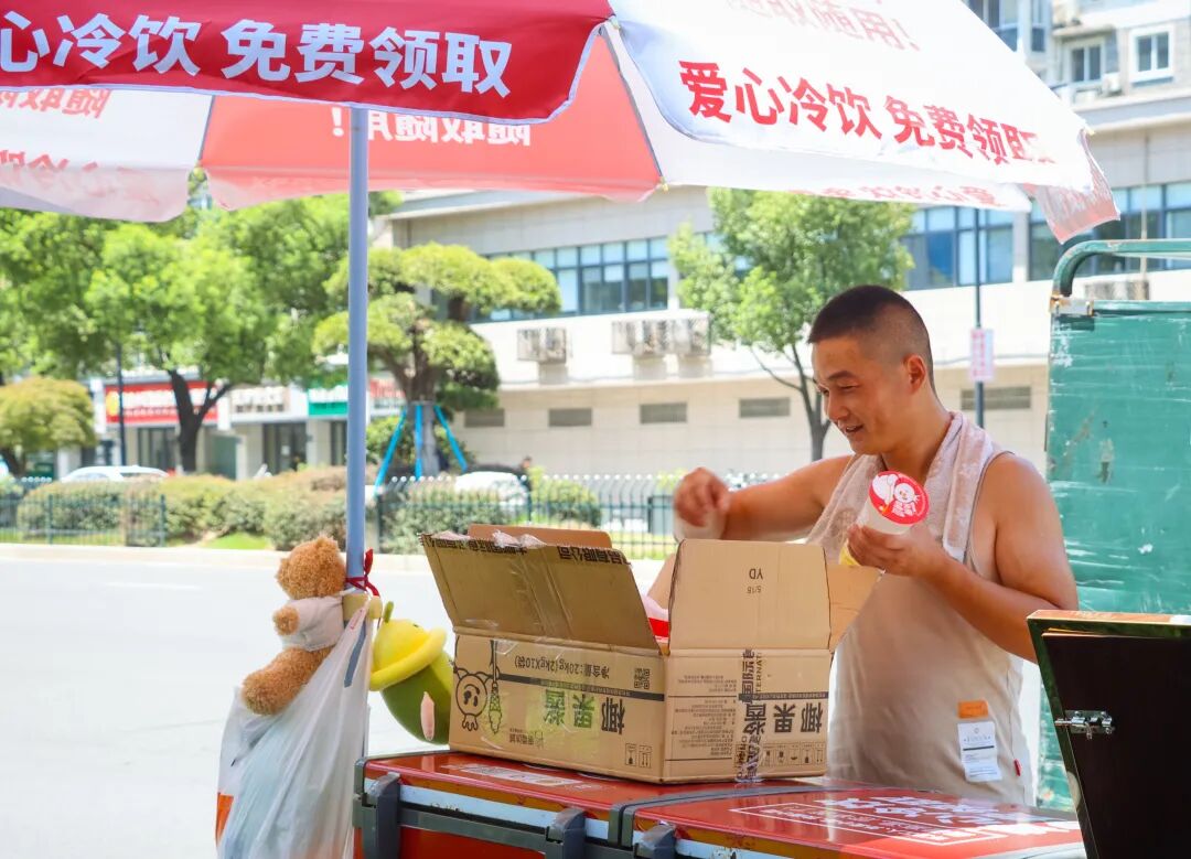 爱心人士为爱心冰柜添加消暑饮品。