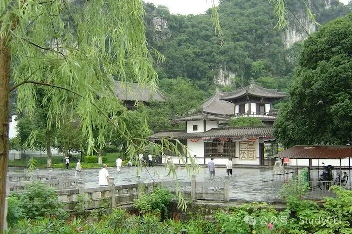 A white traditional Chinese building surrounded by a walkway and flanked by karst mountains in Guilin's Seven Star Park