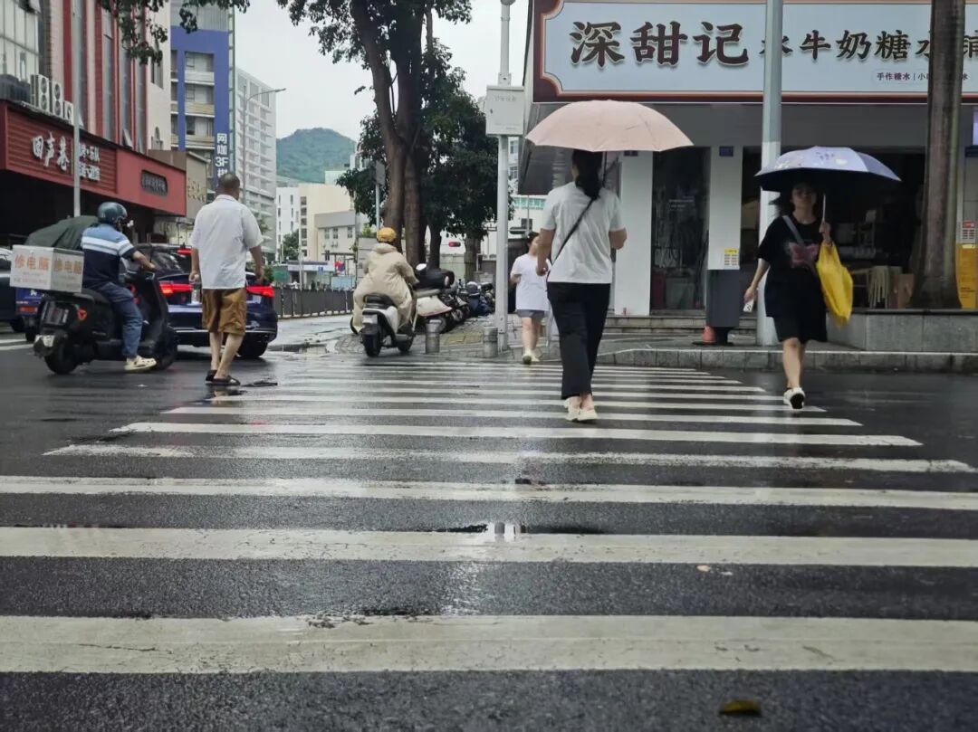▲ 2026年7月31日，雨后深圳街头，行人们正在通过一处十字路口。（南方周末实习生 黄渝/摄）