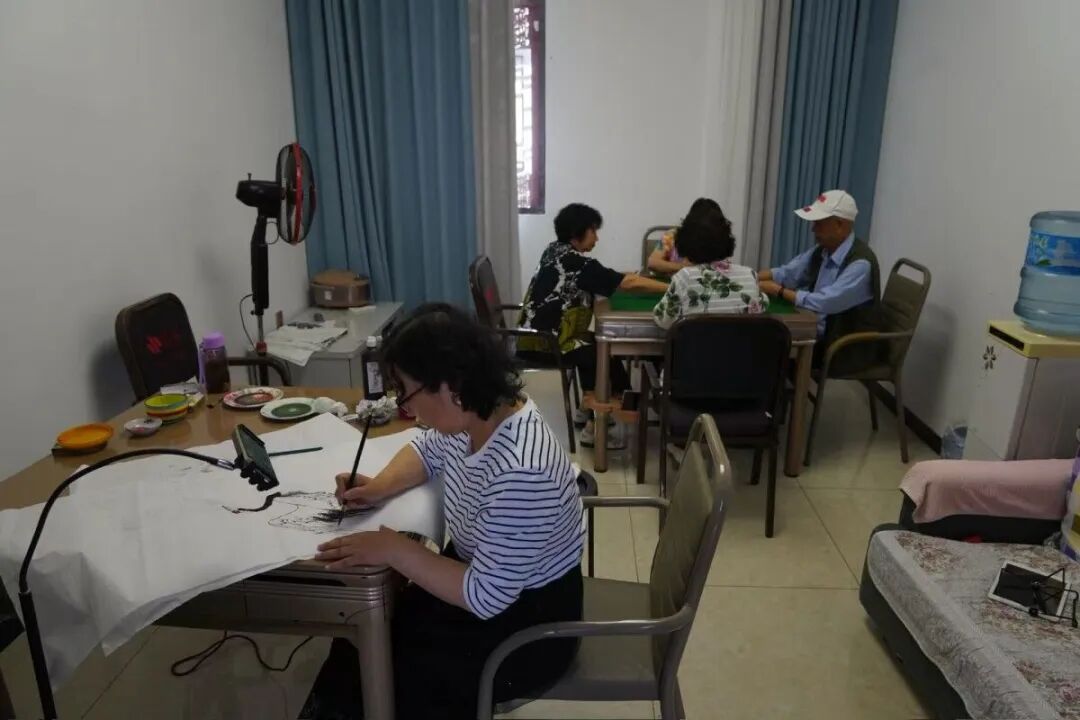老人在大龙社区旅居客栈的活动室里写字、打牌。