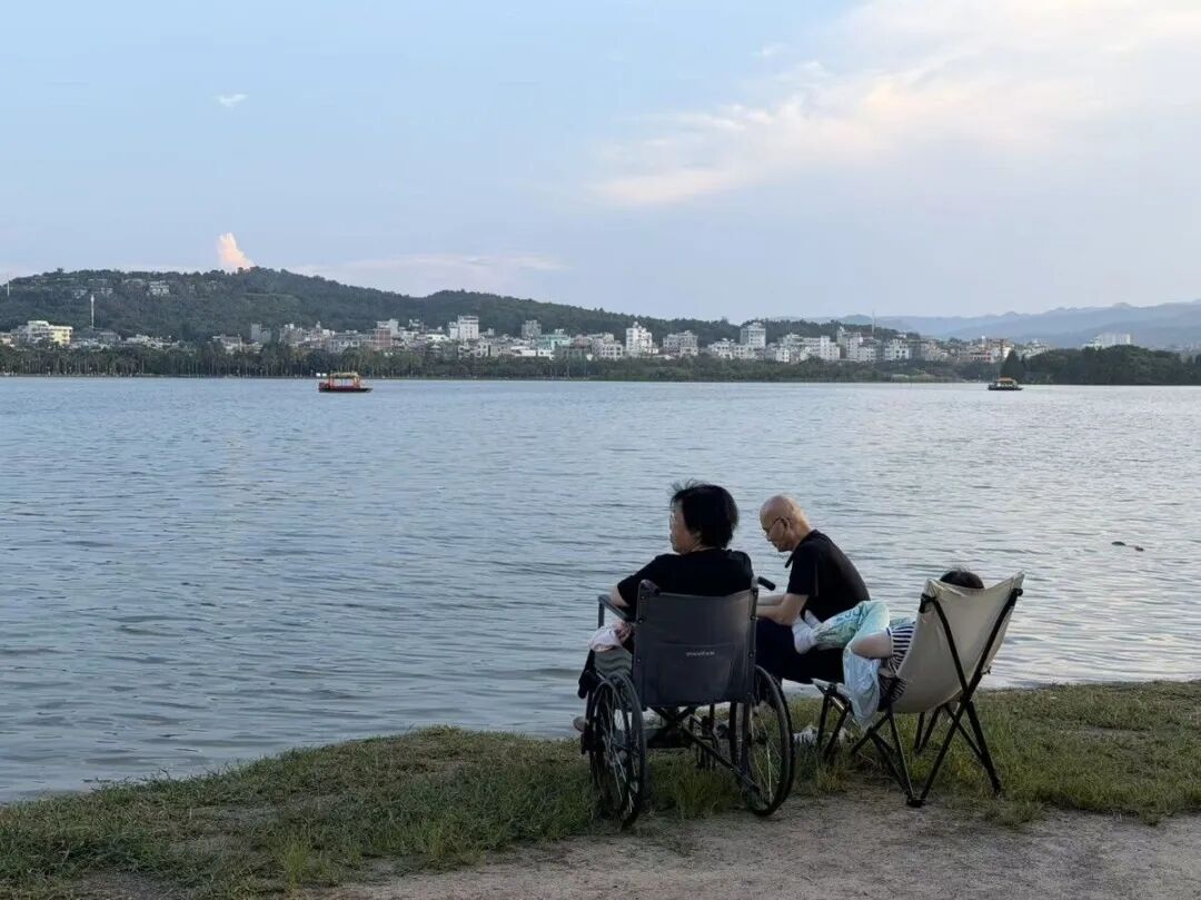几位老人坐在弥勒湖泉生态园的湖边休息。